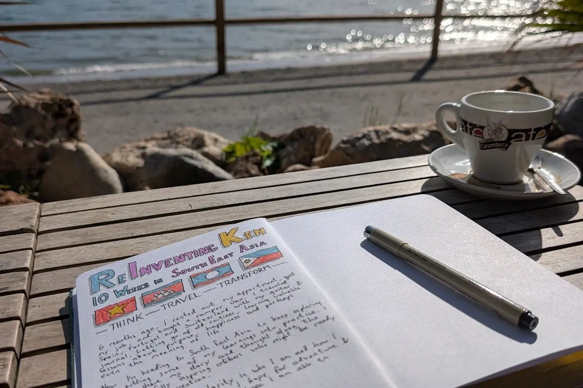 An open journal and a coffee on a terrace by the sea