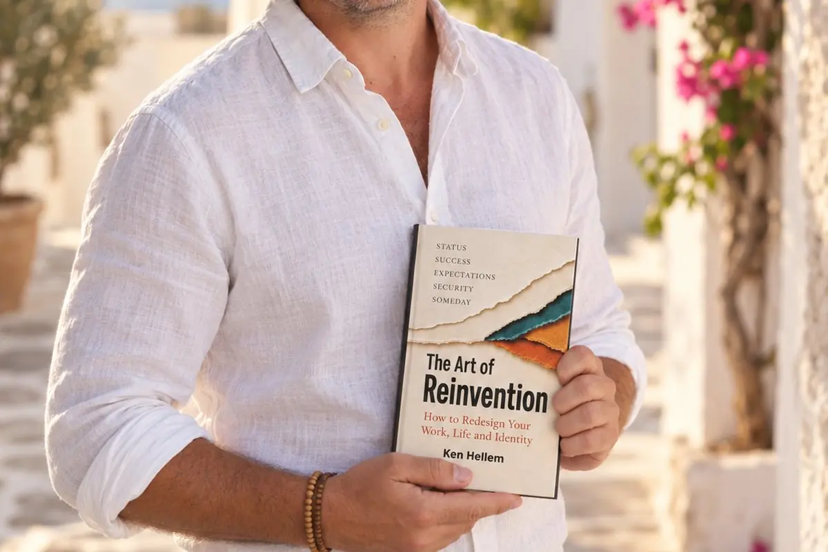 Ken Hellem in a white shirt holding a copy of The Art of Reinvention