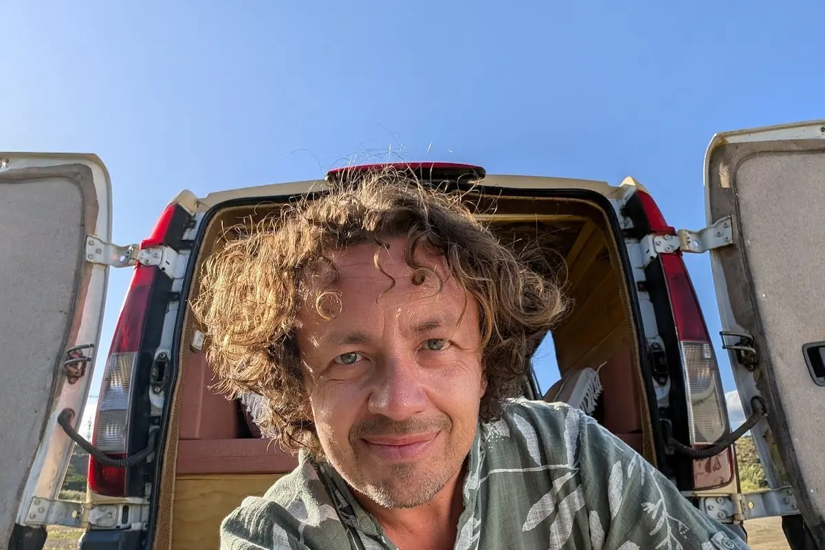 Ken Hellem sitting at the open back doors of his camper van