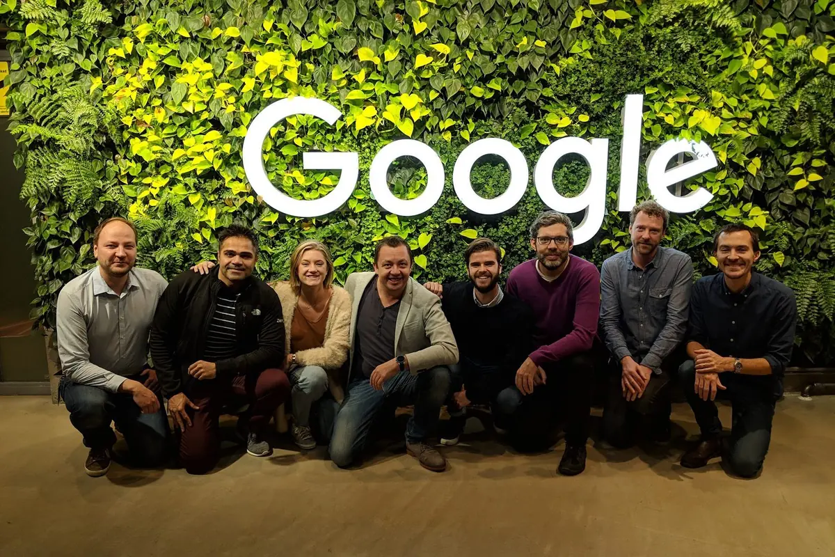Ken Hellem with his team in front of the Google logo wall