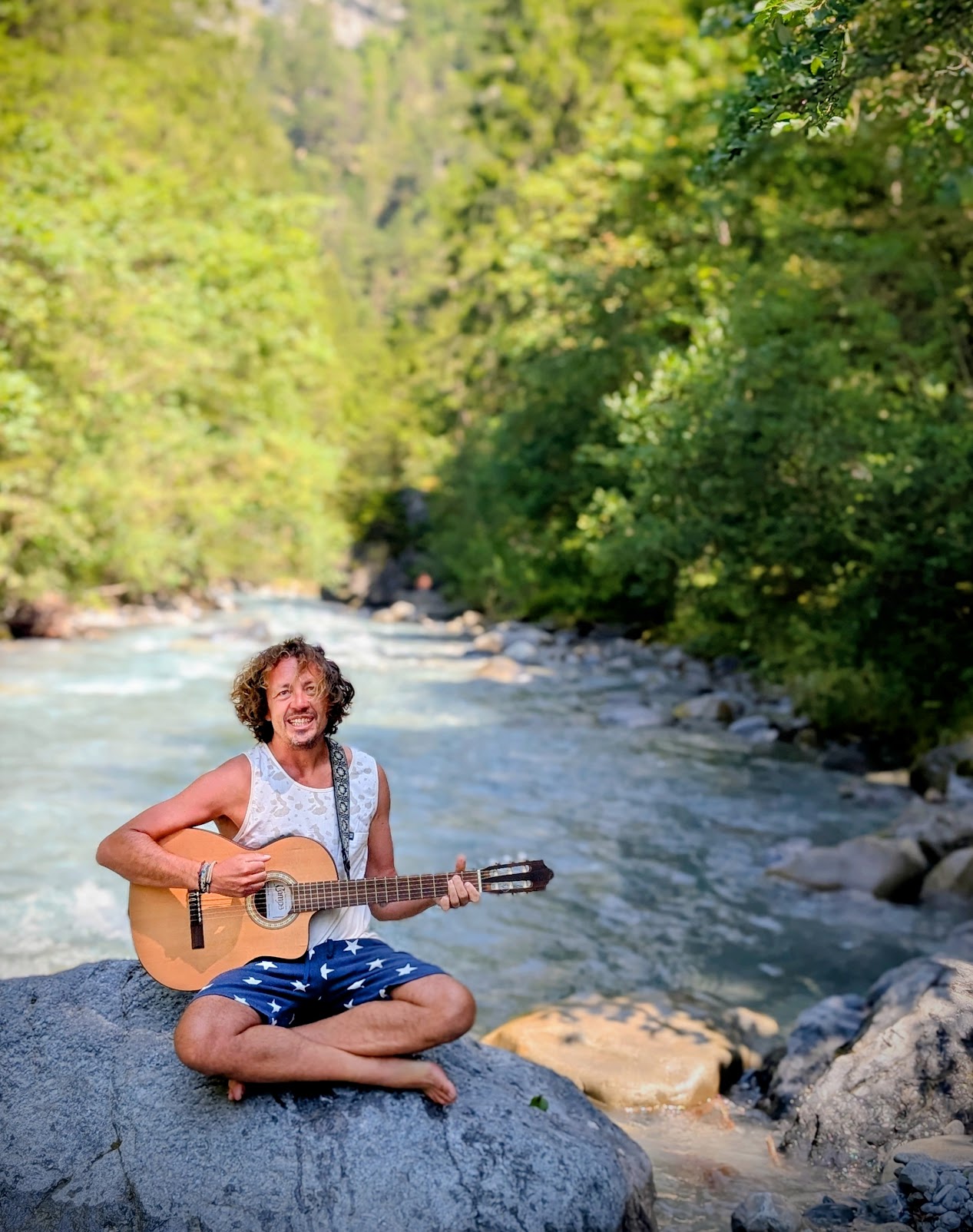 Ken playing guitar by river
