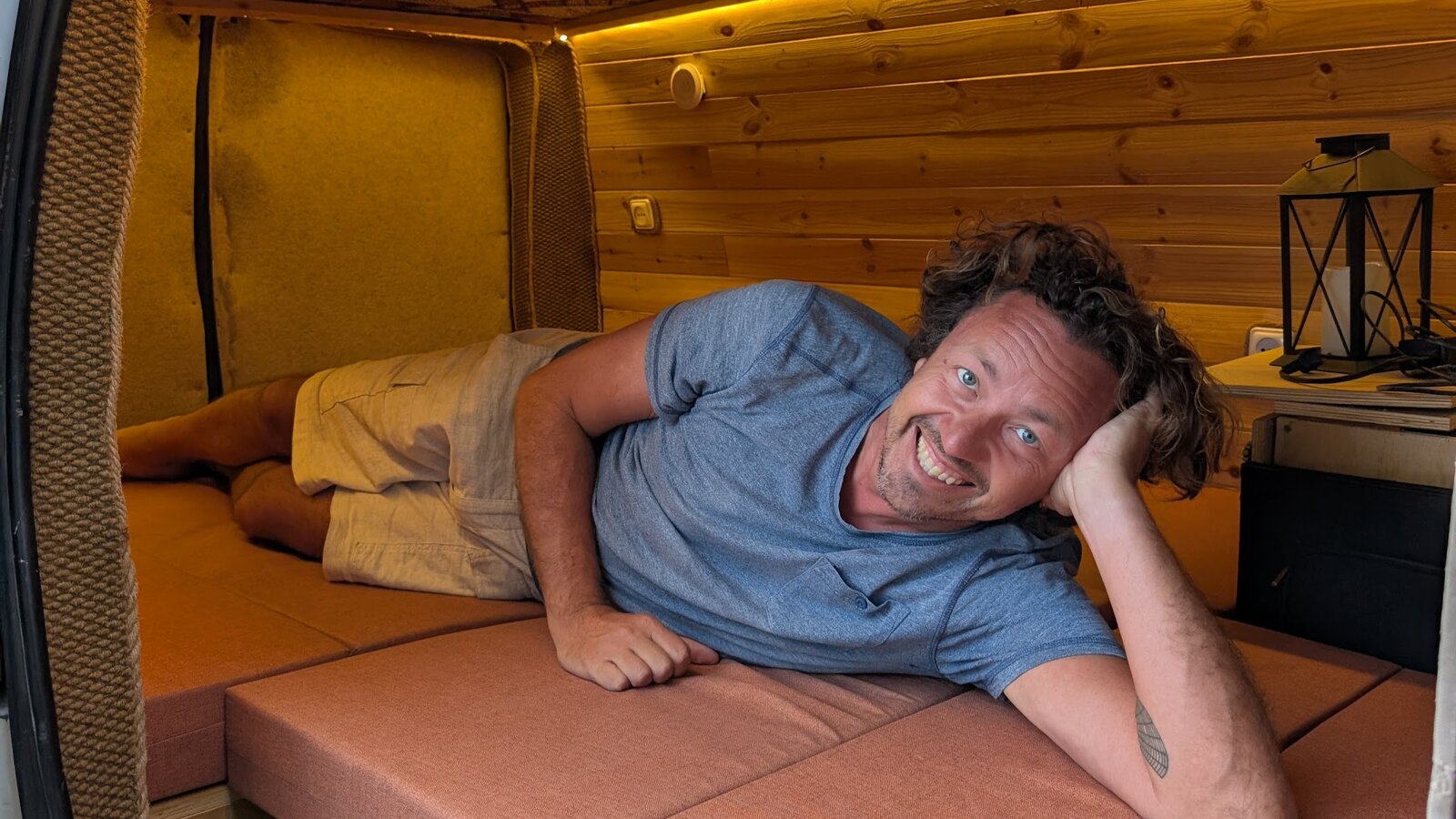 Ken Hellem relaxing inside a converted campervan, smiling